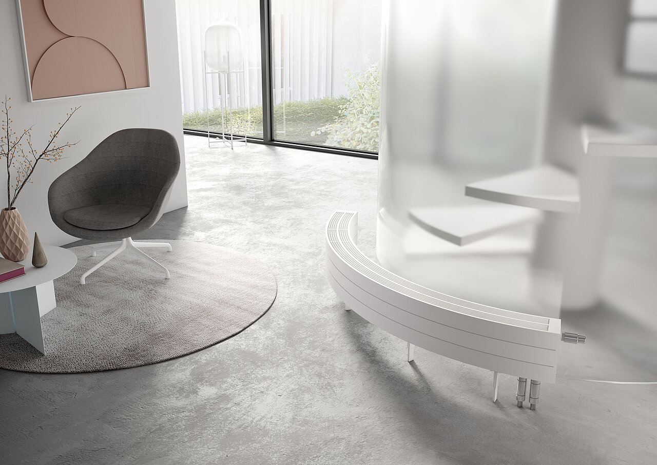 Wohnraum mit einem modernen grauen Stuhl auf einem runden Teppich, einem kleinen Tisch. Im Vordergrund ist ein gebogener weißer Heizkörper zu sehen.