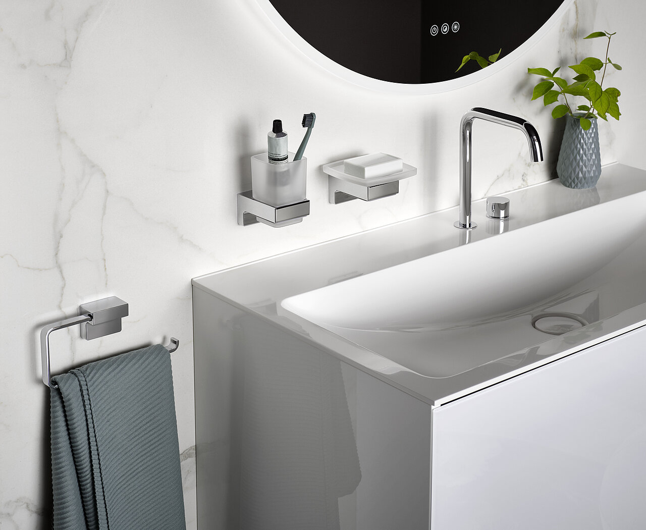 Ein Waschbecken mit einem verchromten Wasserhahn, einer weißen Arbeitsplatte und montierten Zubehörteilen, die Seife, Lotion und eine Zahnbürste enthalten.