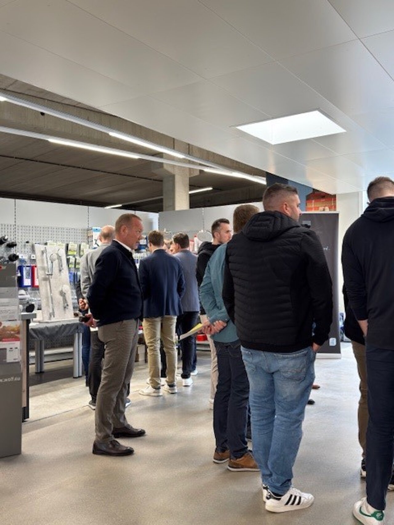 Eine Gruppe von Menschen steht in der Sanitär-Heinze Bäderausstellung zwischen modern gestalteten Badinstallationen und stilvollen Ausstellungsstücken.