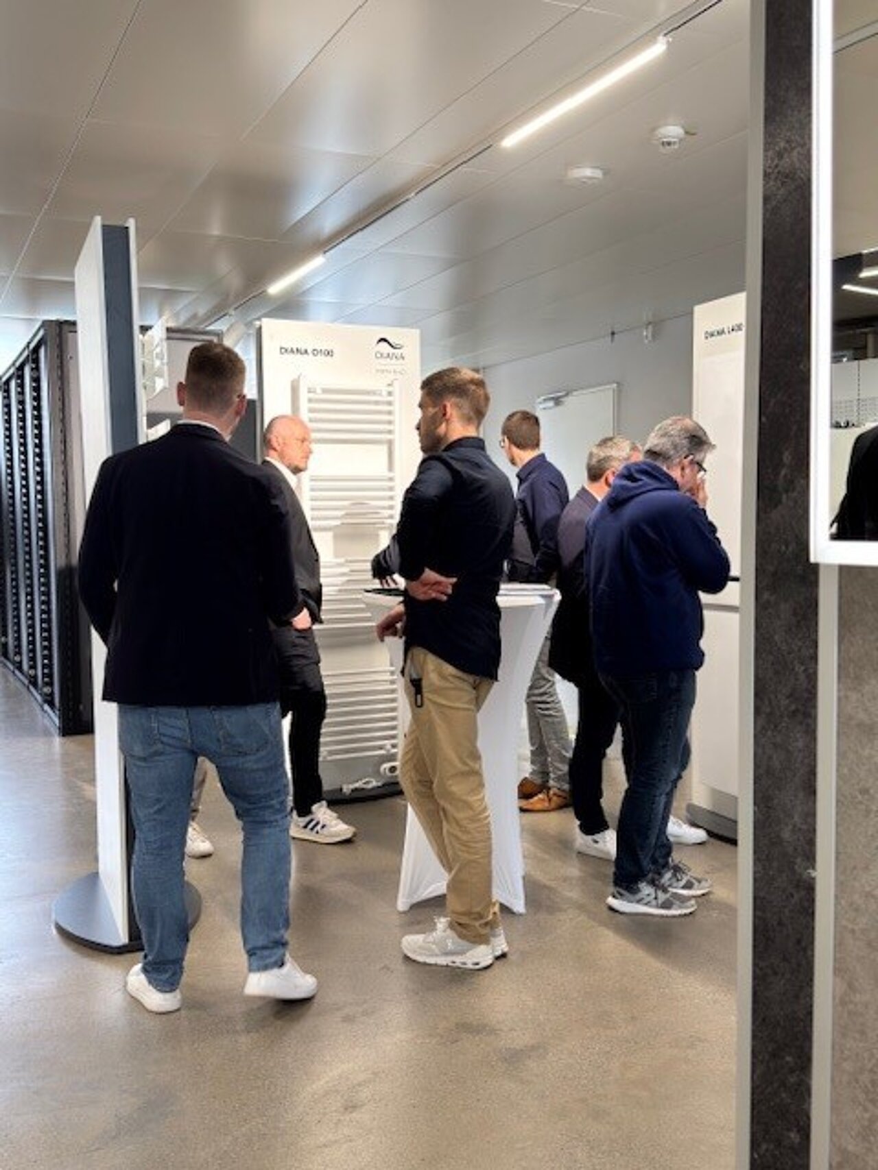 Mehrere Männer stehen in einem modernen Ausstellungsraum und unterhalten sich. 