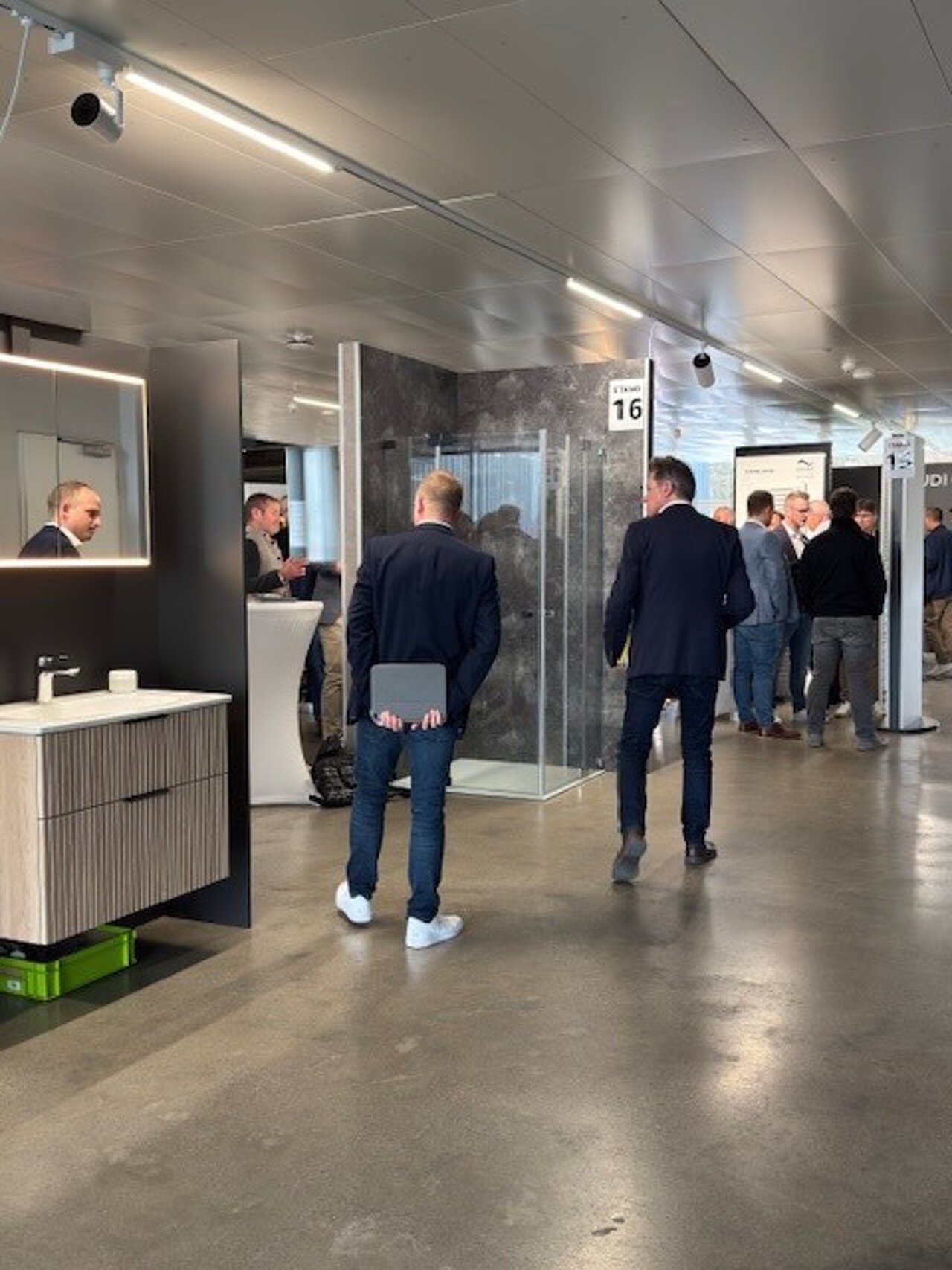 Menschen in Geschäftskleidung gehen durch einen modernen Ausstellungsraum der Sanitär-Heinze Bäderausstellung