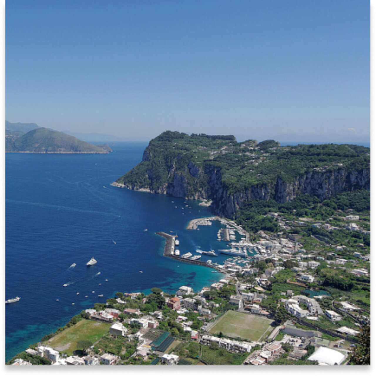  Luftaufnahme einer Küstenstadt mit weißen Gebäuden, üppig grünen Klippen.