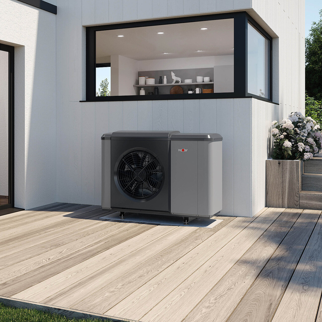 Ein graues Wärmepumpengerät ist auf einer Holzterrasse vor einem weißen Haus mit großen Fenstern installiert.