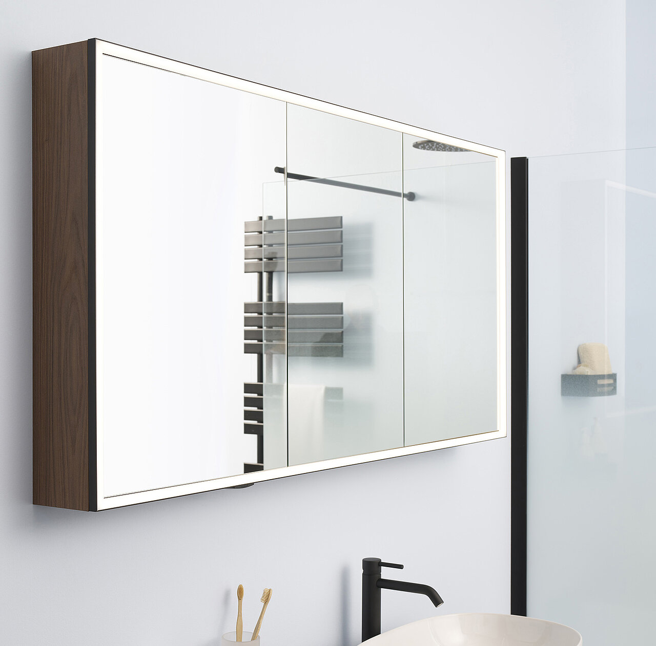 An der Wand montierten Spiegelschrank mit dunklen Holzseiten und integrierter Beleuchtung.