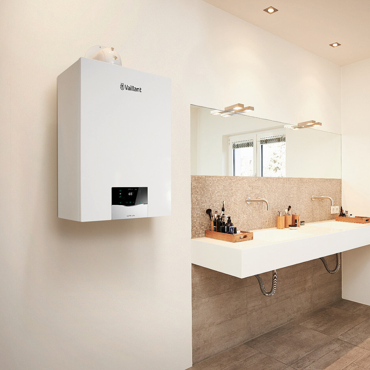 Ein Badezimmer mit Doppelwaschbecken, einem großen Spiegel und einem weißen, an der Wand montierten Vaillant Gas-Brennwerttherme.