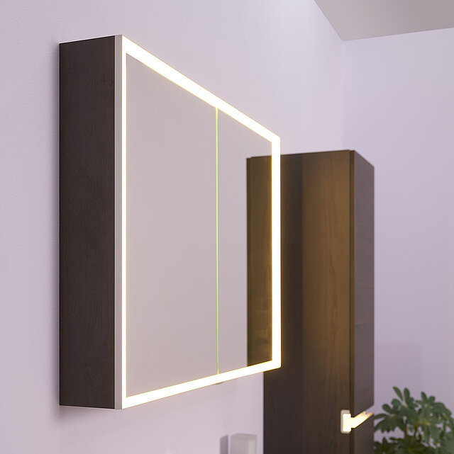 Moderner, wandmontierter Badspiegelschrank mit LED-Beleuchtung an den Rändern in warmweißem Licht.