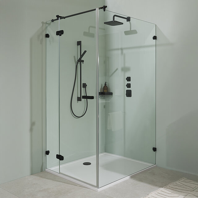 Eine moderne, rahmenlose Glasduschkabine mit schwarzen Armaturen, einer Regendusche, eine Handbrause und an der Wand montierte Bedienelemente.