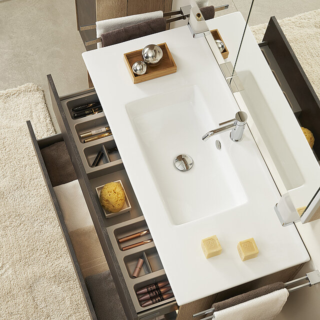 Ein modernes Waschbecken mit einer weißen Arbeitsplatte und geordneten Schubladen.