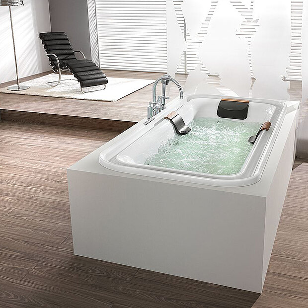 Modernes Bad mit weißem, rechteckigem Whirlpool mit sprudelndem Wasser, Kopfstützen und Armlehnen