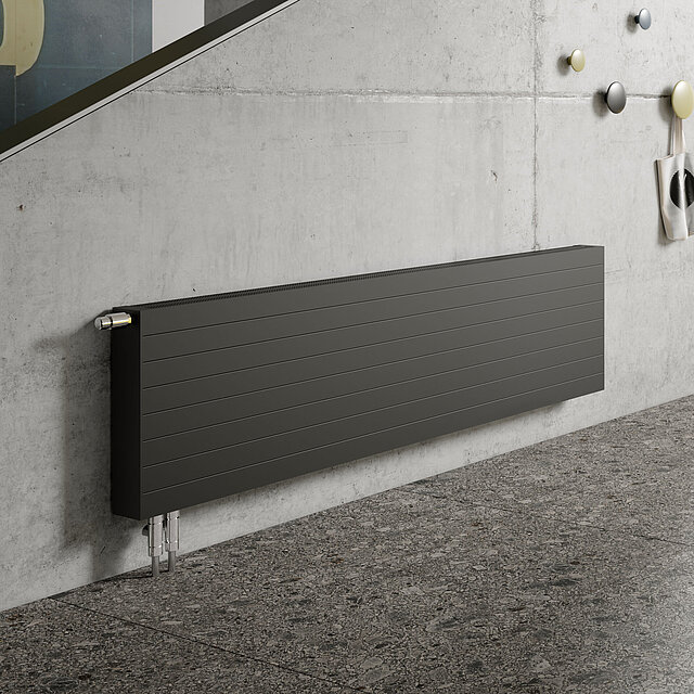 Ein modernes Wohnzimmer mit großen Fenstern, blauen Sofas, abstrakter Wandkunst und einer Betontreppe mit einem schlichten schwarzen Heizkörper.