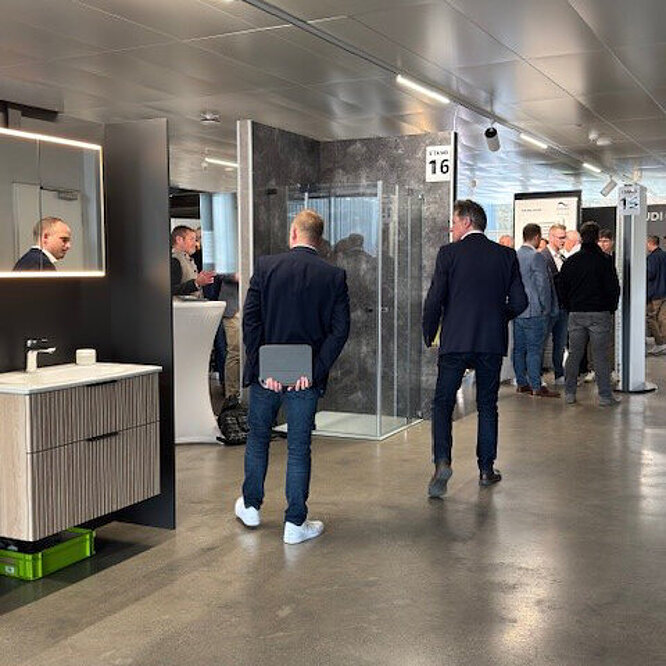 Menschen in Geschäftskleidung gehen durch einen modernen Ausstellungsraum der Sanitär-Heinze Bäderausstellung