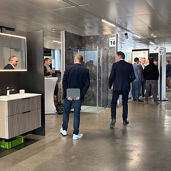 Menschen in Geschäftskleidung gehen durch einen modernen Ausstellungsraum der Sanitär-Heinze Bäderausstellung