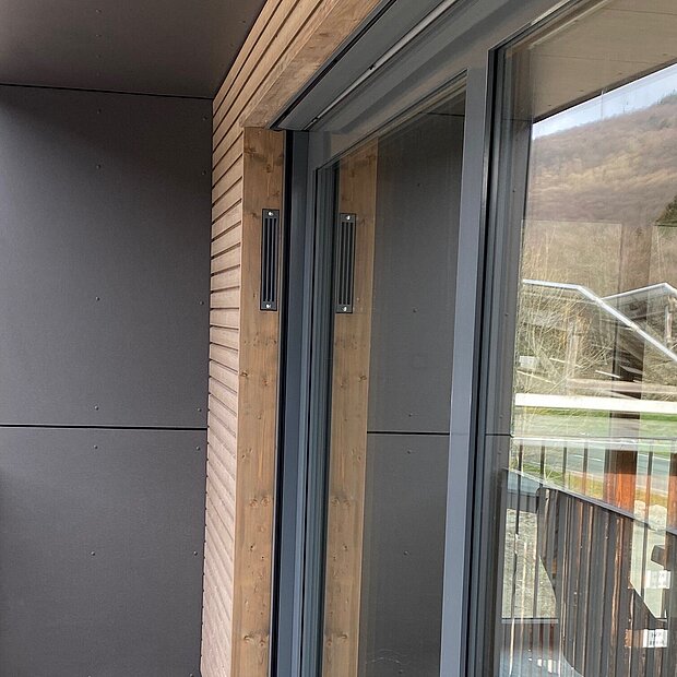 Ein moderner Balkon mit holzgetäfelten Wänden und Fußböden, großen Glasschiebetüren.