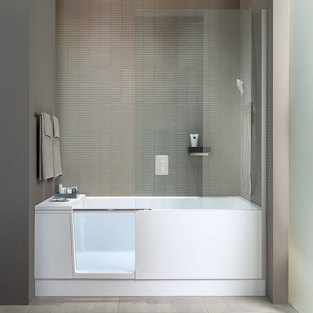 Ein modernes Badezimmer mit einer weißen Badewanne mit Glastür, einer an der Wand montierten Duschbrause.